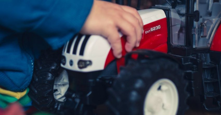 Tractor Performance - Person in Blue Jacket Holding Red and White Tractor Toy