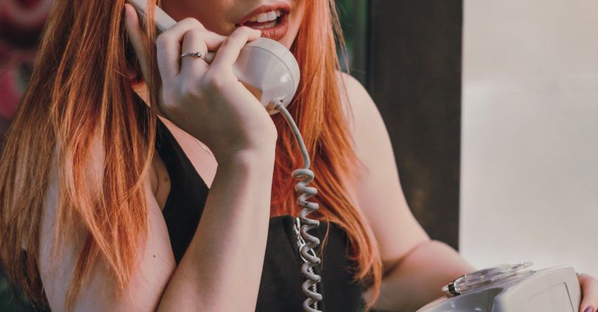 Rotary Tillers - Stylish young redhead lady talking by vintage rotary telephone