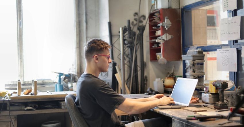 Maintenance Plan - Focused man working on laptop in workshop