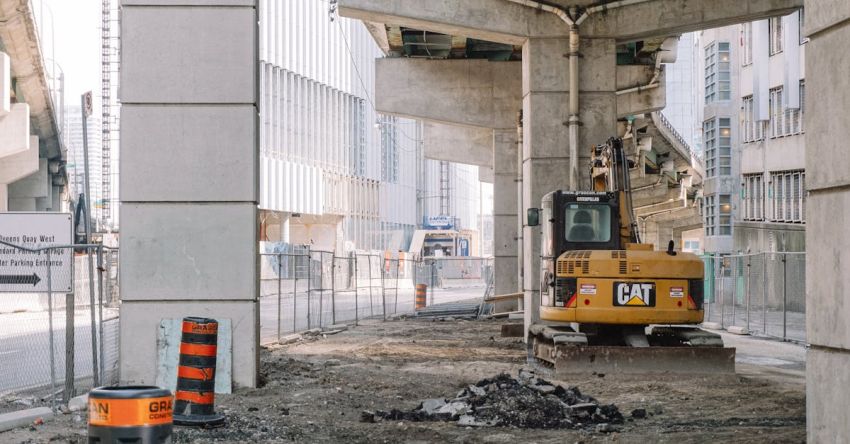 Machinery Maintenance - Site of roadway under concrete bridge construction with heavy equipment on dirty ground