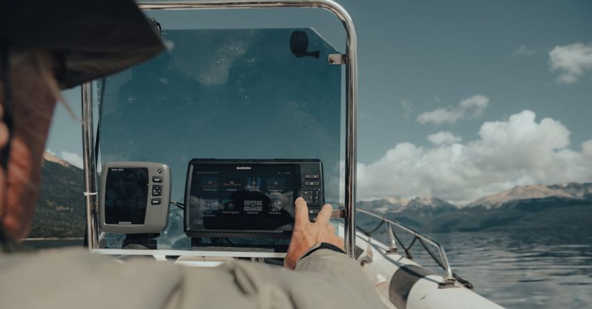 Plowing Technology - A man is looking at his tablet while driving a boat