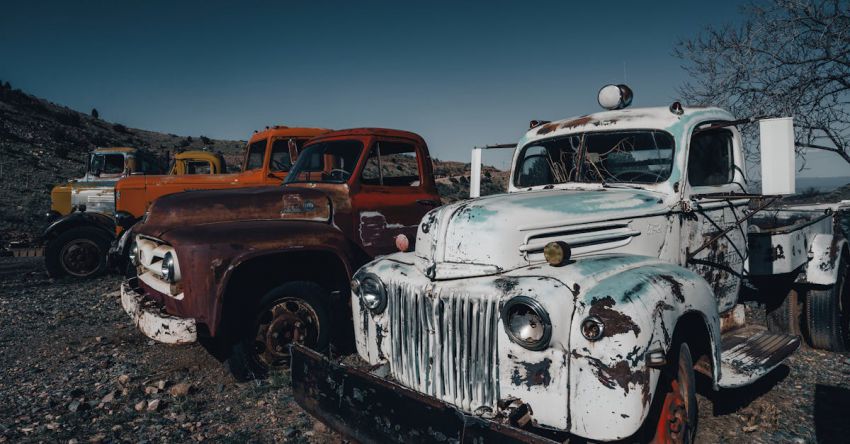 Tractors - Old trucks parked in a field with dirt and rocks